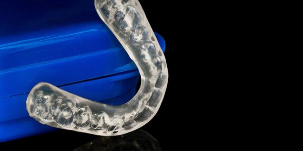 clear mouth guard on a black background leaning against a blue case