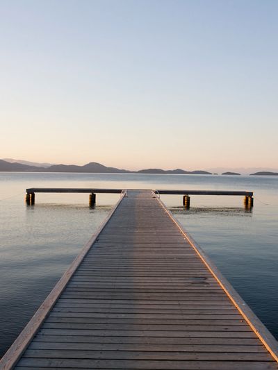 The dock narrows into the distance, symbolizing the long and uncertain path of family estrangement.