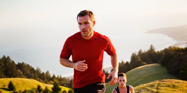 Two people running uphill in a scenic outdoor setting.