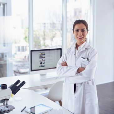 Female scientist in lab coat standing confidently in a modern lab.