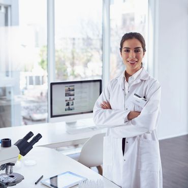 Confident female scientist in white lab coat in a bright laboratory.