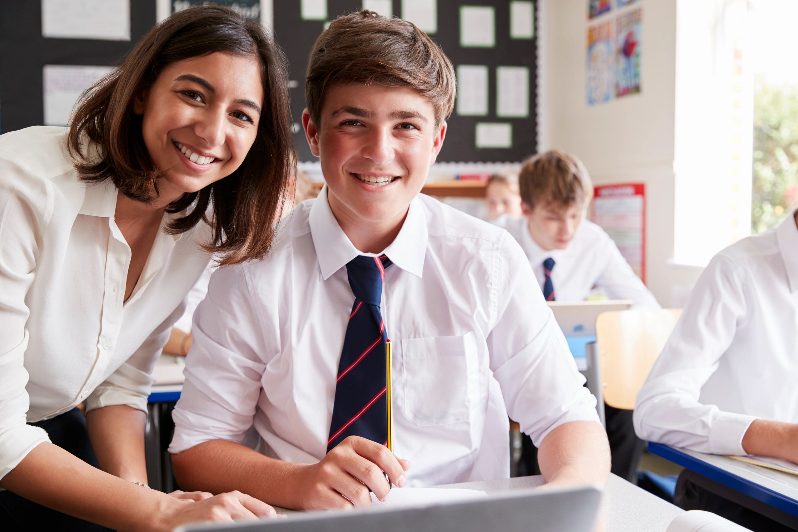 Smiling teacher and student in a classroom setting.