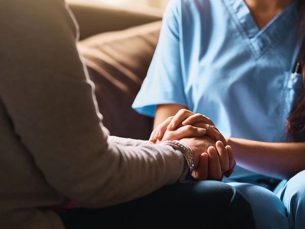 Caregiver offering comfort by holding a patient’s hands during recovery from medical negligence