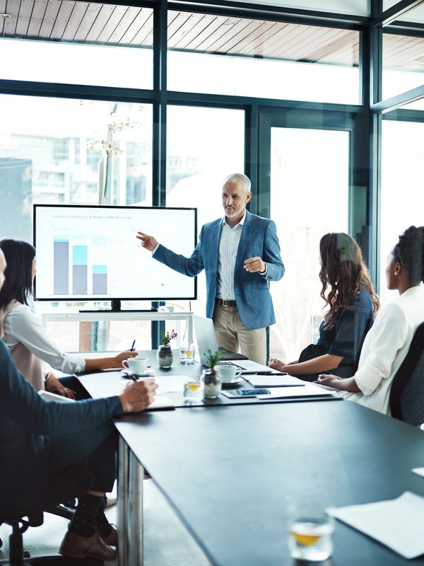 A business presentation with a man explaining charts to attentive colleagues in a modern office.