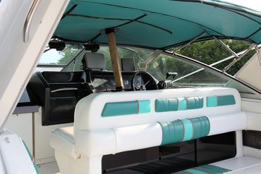 Boat interior with teal and white seats and a wooden support beam.