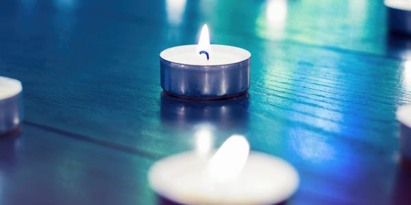 Lit tealight candles on a reflective surface with a cool blue hue.