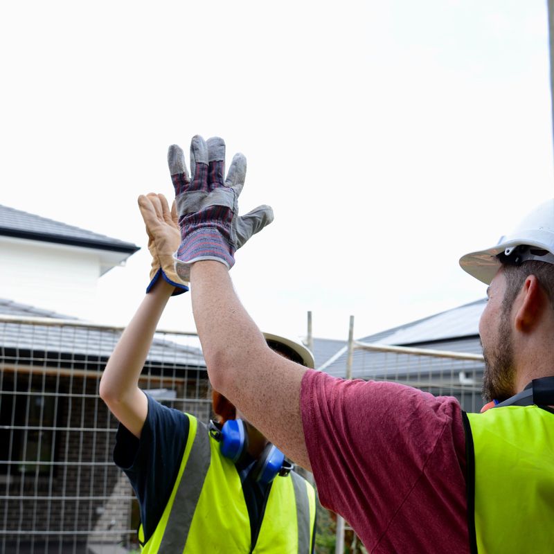 Male and female construction worker hand motioning a high-five