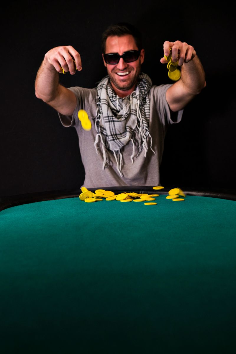 Young man poker player collecting a pot of chips at a poker table.