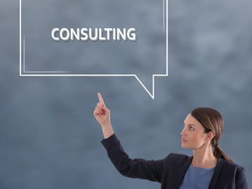 Businesswoman pointing to the word CONSULTING in a speech bubble.