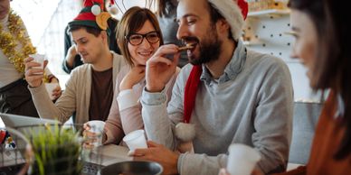 Friends enjoying a festive holiday party with Santa hats and snacks.
