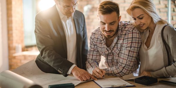 Couple signing documents with a professional's guidance in a bright office.