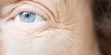 Close-up of an elderly person's blue eye with visible wrinkles around it.