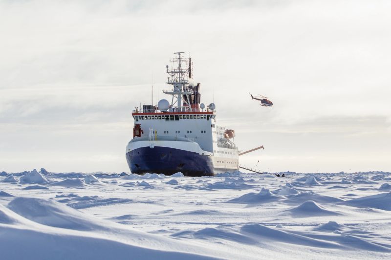 Research icebreaker docked to an ice floe and and a helicopter recently took off from the helideck while setting up an ice camp