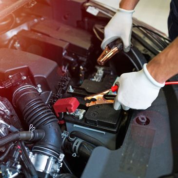 Person preparing to jump-start a car battery with jumper cables.
