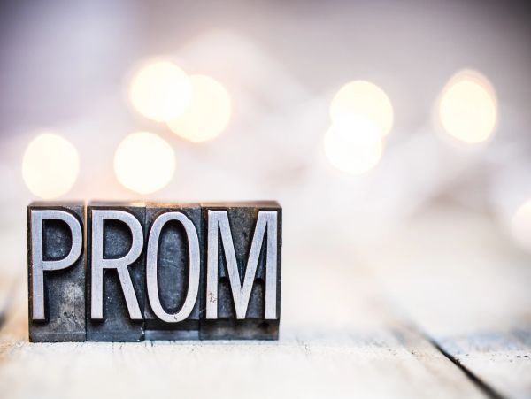 Metal letter blocks spelling PROM with soft lights in background.