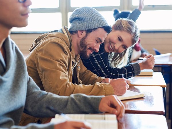 Students studying and smiling together in a classroom.