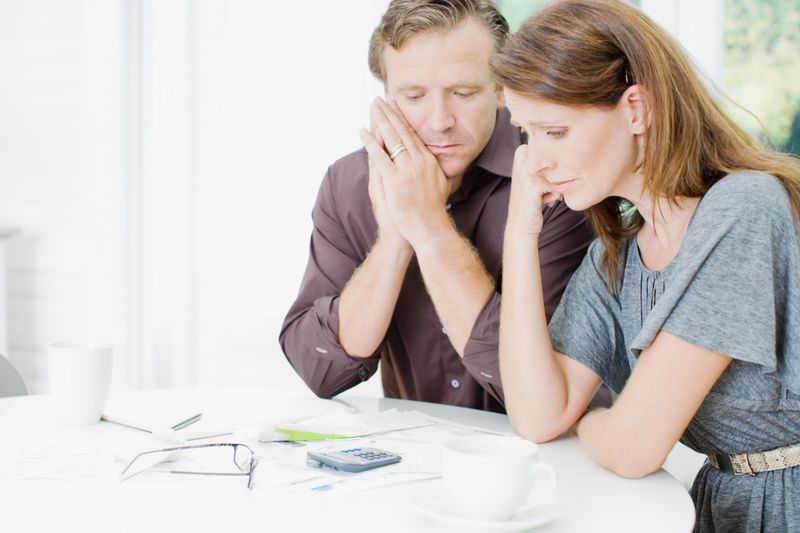 Worried couple at table paying bills