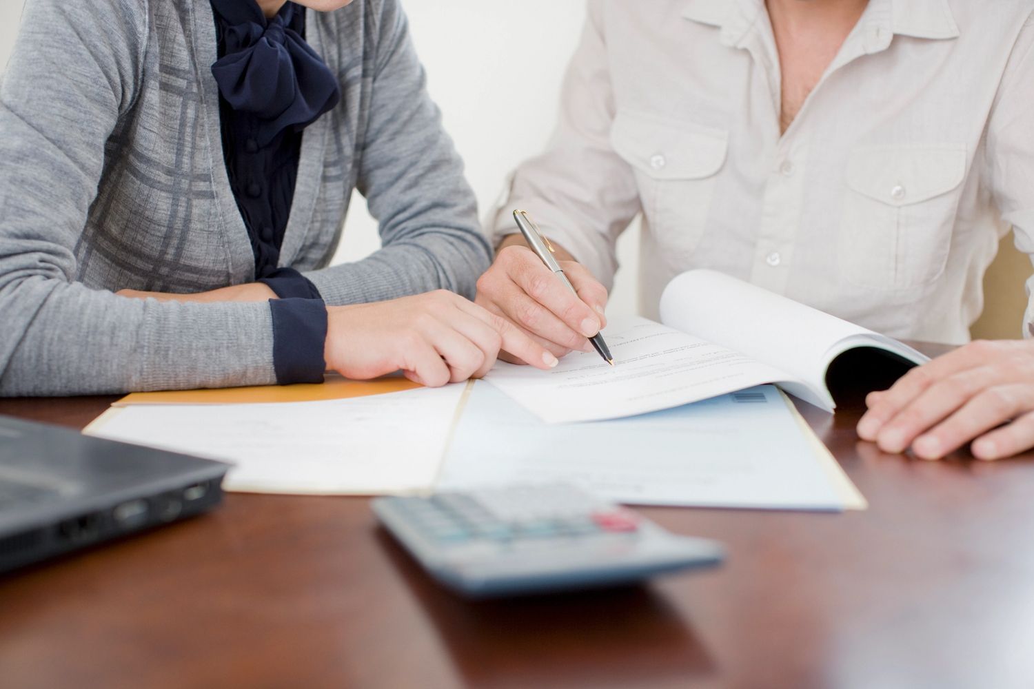 Two people reviewing and signing documents together at a table.