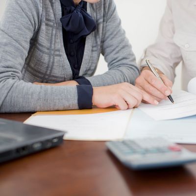Two people signing paperwork at a desk.
