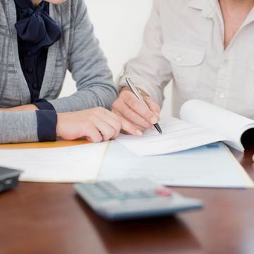 Two people reviewing and signing documents together at a table.