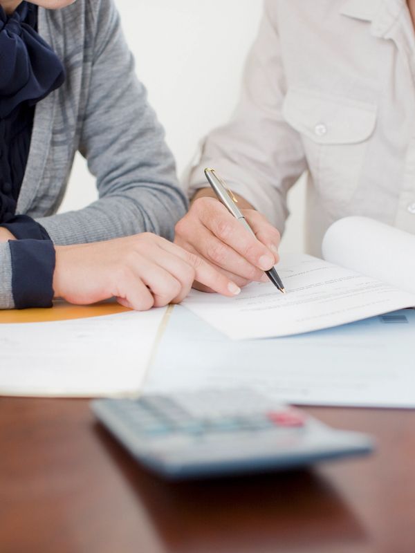 Two people reviewing and signing documents together at a table.