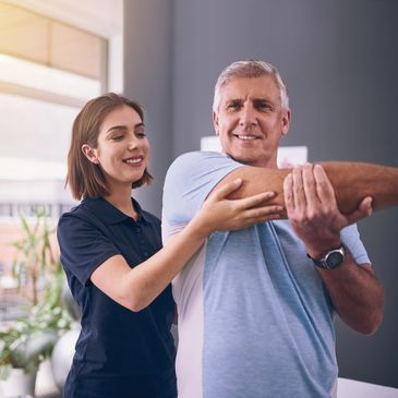 A therapist assists an older man with arm stretches in a bright room to do sports massage
