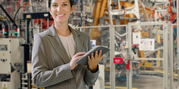 Professional woman in a suit using a tablet in a modern industrial factory.
