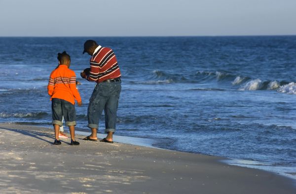 Two people walking along a sandy beach near the ocean.