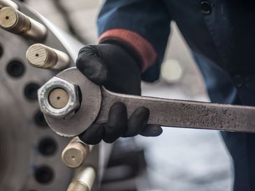 Worker using a large wrench on industrial equipment.