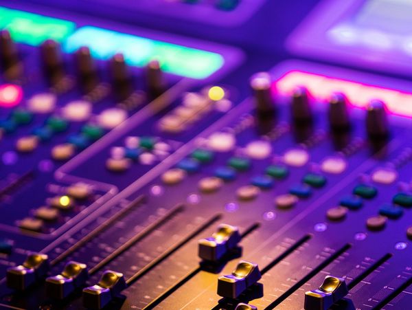 Close-up of an audio mixing console with colorful lights.