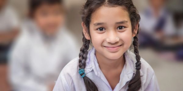 Smiling schoolgirl with braided hair in classroom.