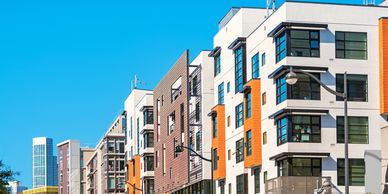Modern apartment buildings with orange accents under a clear blue sky.