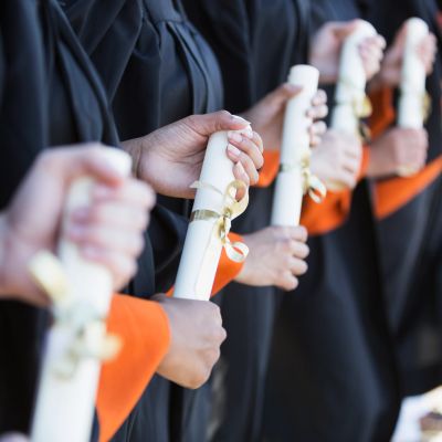Graduates holding diplomas in a row.