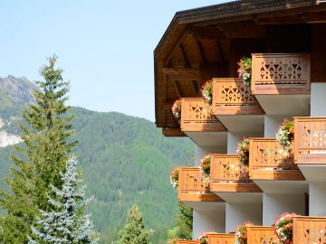Wooden balconies with flowers overlooking a mountain landscape.