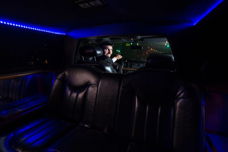 View from the back seat of a limo of the smiling driver looking back through the divider.