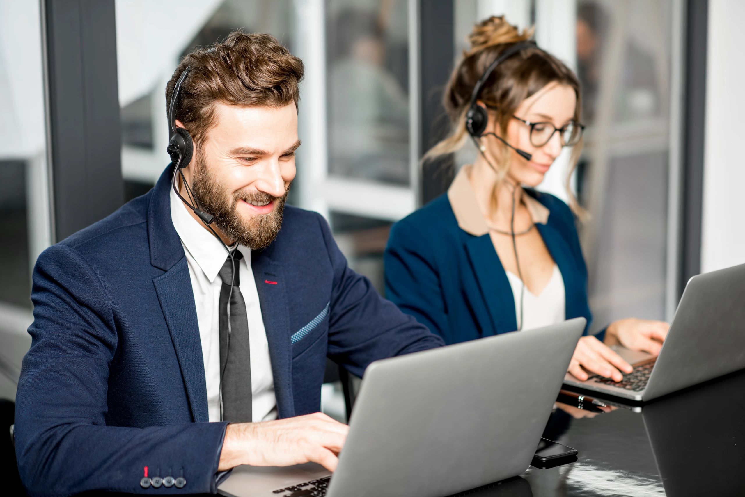 Two customer service agents working with headsets and laptops.