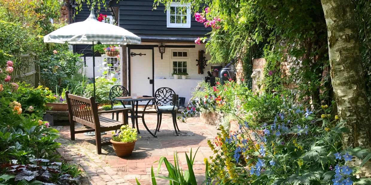 Cozy garden patio with seating and flowers.