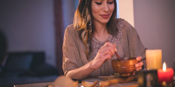 A woman in traditional attire stirring a bowl by candlelight.