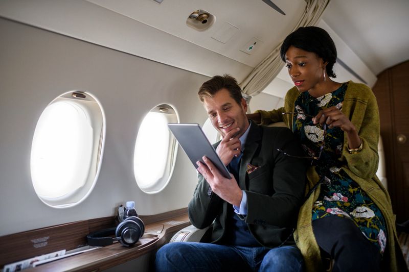 Multiethnic heterosexual couple inside private jet airplane during the flight.