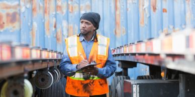 Worker inspecting around trailers in safety vest.