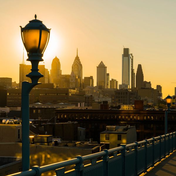 Philadelphia skyline at sunset with glowing street lamps.