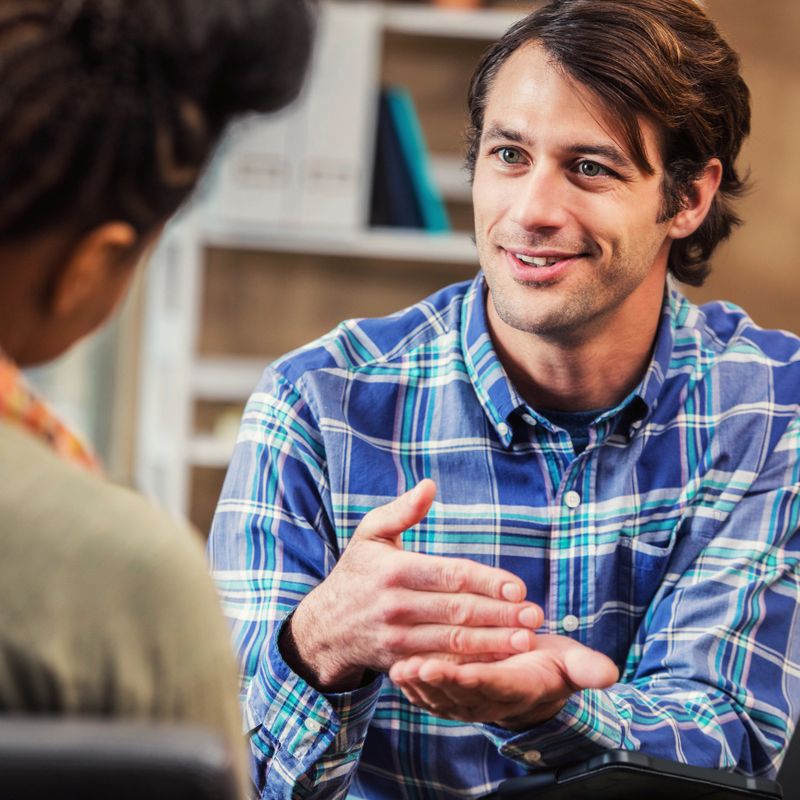 Handsome businessman discusses business with an unrecognizable colleague or client.