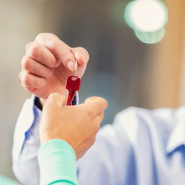 Person handing over a red key to another person.