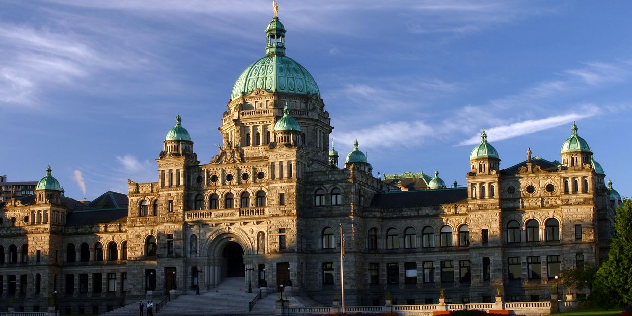 Grand historic building with multiple green domes under a clear blue sky.