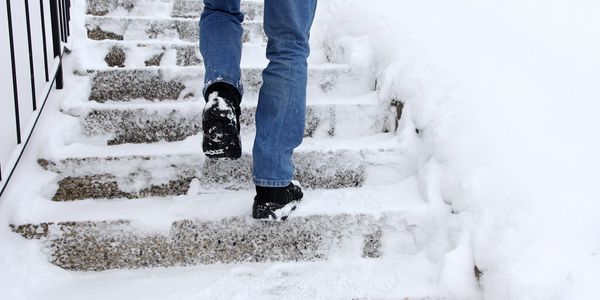image of a person climbing slippery ice and snow covered steps in the winter time. 