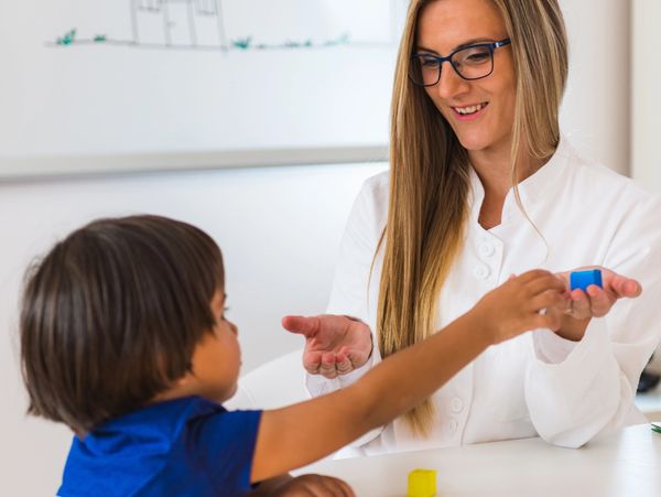 Therapist working with a child using colorful blocks during a session.