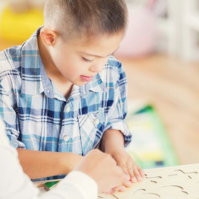 Young boy engaged in a hands-on learning activity with assistance.