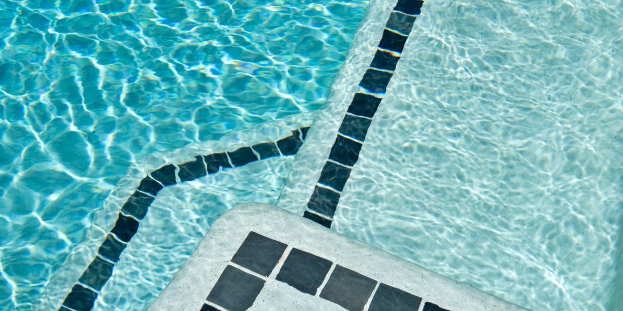 Close-up of a professionally installed pool waterline tile with clean lines and vibrant colors, addi