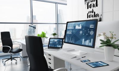 Modern office desk with multiple screens showing data charts.