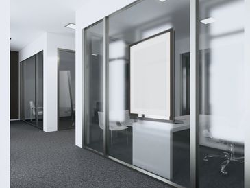 Modern office hallway with glass walls and minimalistic furniture.